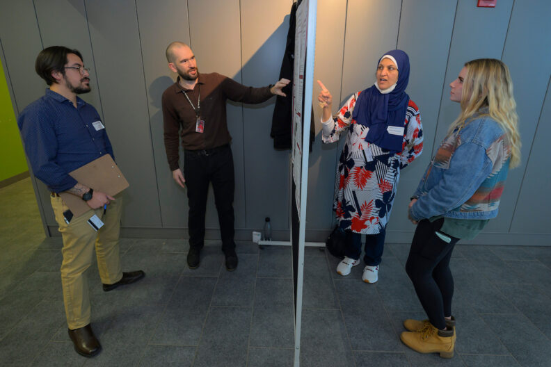 Partition with presenters on each side, both are explaining their research to one other person.