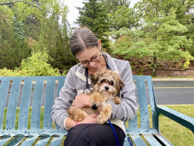 Hailey Briseno sits on a bench with a small dog in her lap.