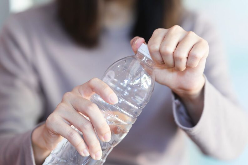 Woman opening a basic plastic water bottle.