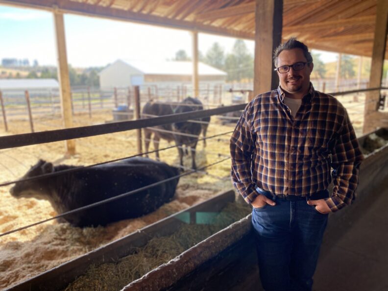 Jesse Bouffiou poses near cattle.