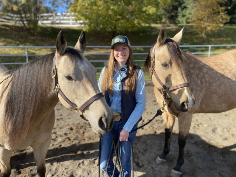 Georgia Jellen poses between two horses.