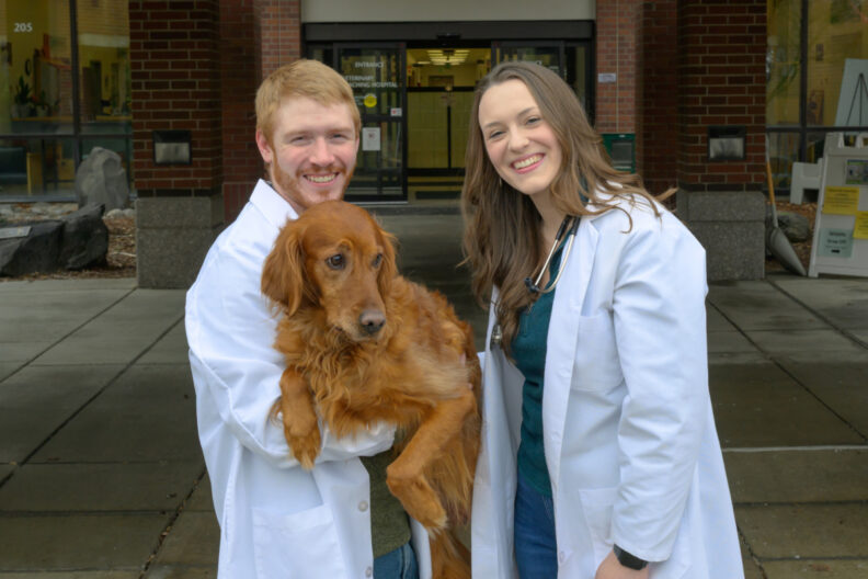 Anna Decan and Nolan Nansel, both fourth-year students in WSU's College of Veterinary Medicine, pose for a photo with their dog, West, near the entrance to the Veterinary Teaching Hospital.