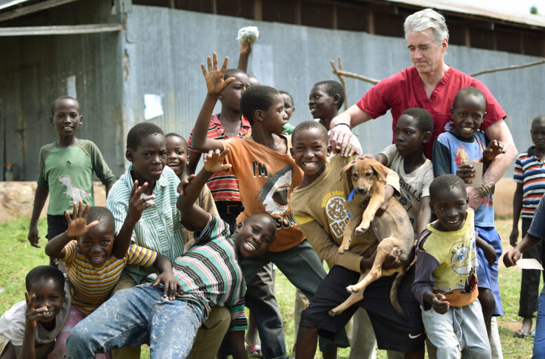 Dr. Palmer in Tanzania with a group of young boys surrounding him.