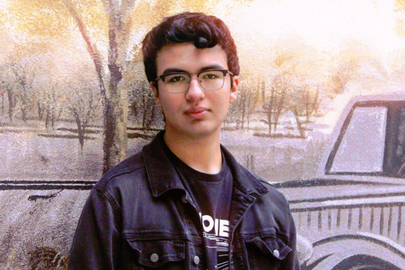 Eric Arreola poses in front of a mural.