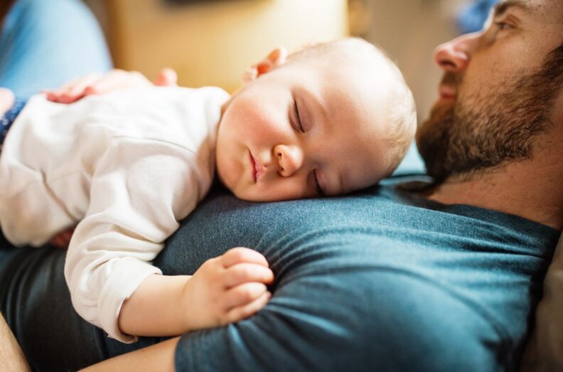 Baby asleep on father's chest.
