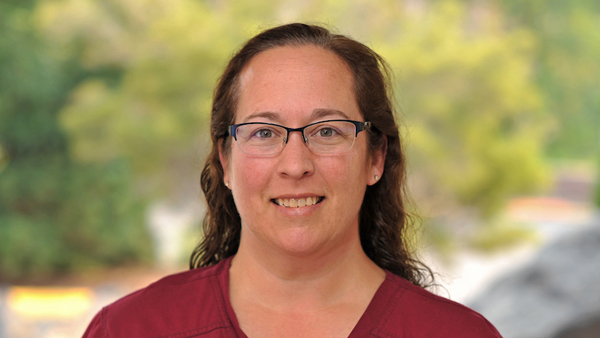 Janel, wearing crimson scrubs, outside the Teaching Hospital.