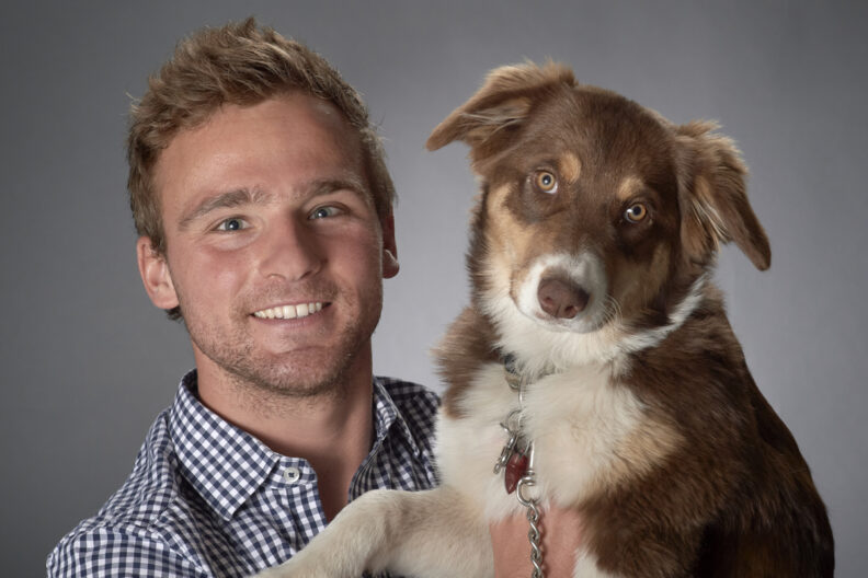 Garrett posing in a photo studio with his dog.