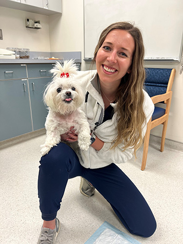 Caregiver in an exam room holding Millie.
