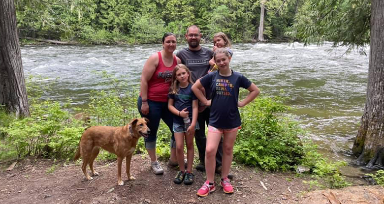 Nina with her family and dog along the bank of a mountain river.