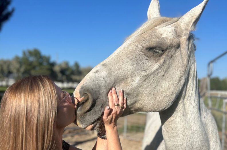Heather kissing Flyer. His eyes are closed.
