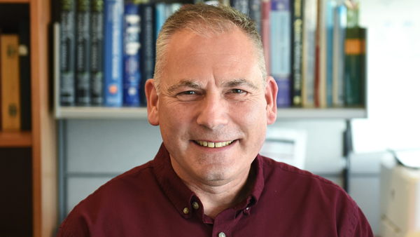 Dr. Snekvik in his office. A bookshelf is behind him.