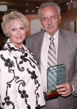 Gene Becker standing next to his wife and holding his award.