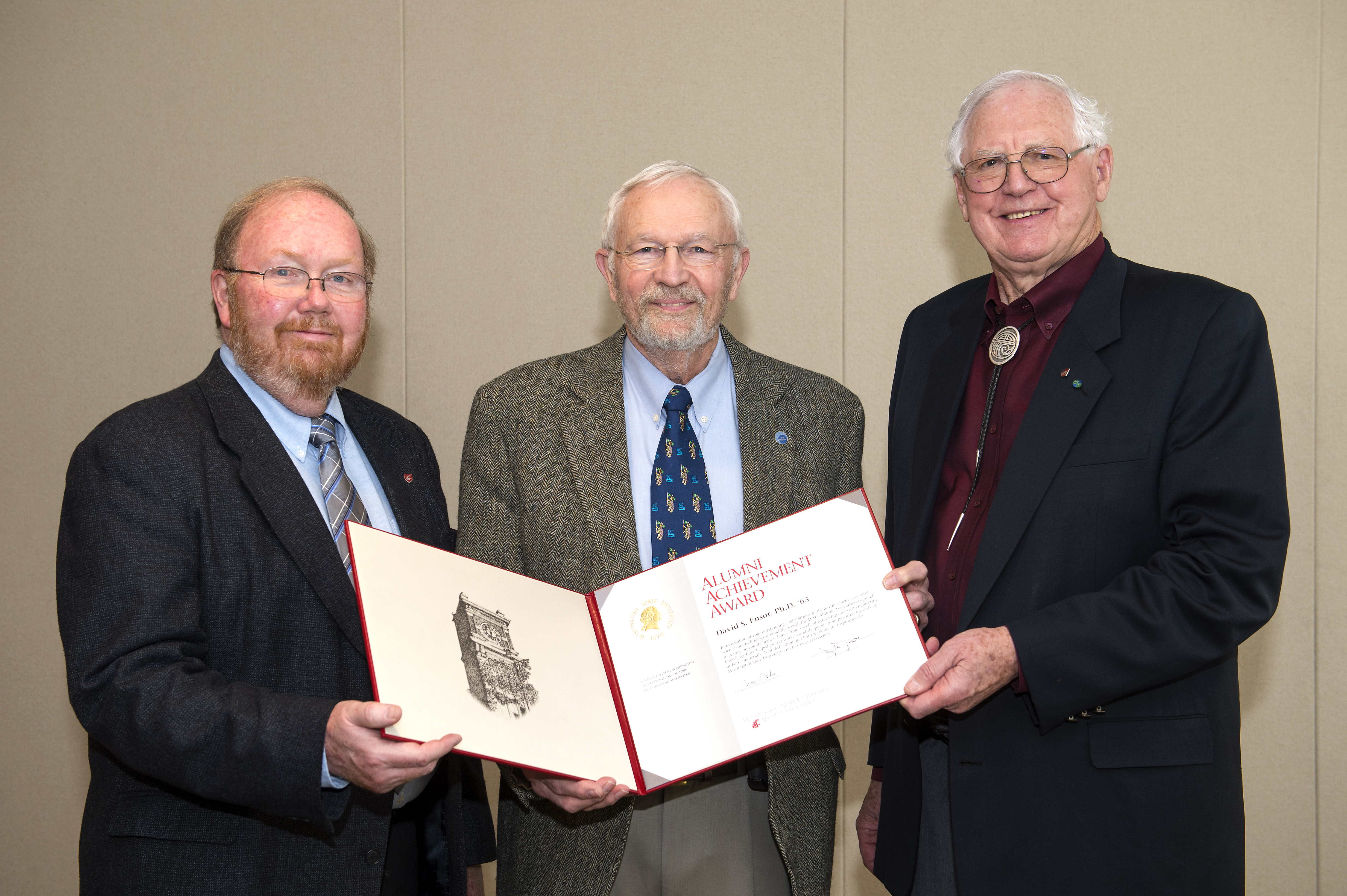 Three men posing with an award.