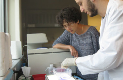 Man pointing at something in a plastic bowl while a woman looks.
