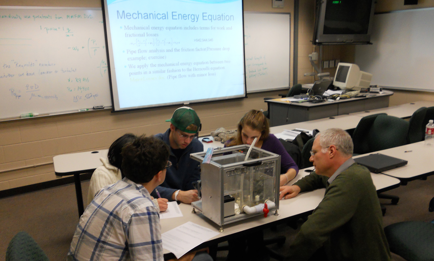 Bernie Van Wie and four students sitting at a table and looking at scientific equipment.