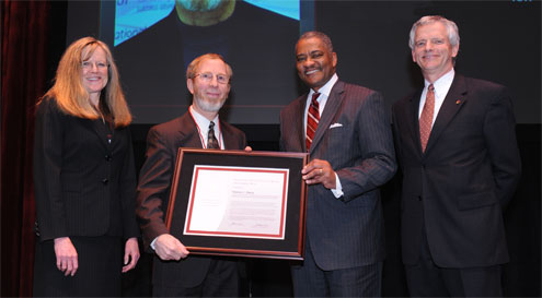 Four people posing with an award plaque.