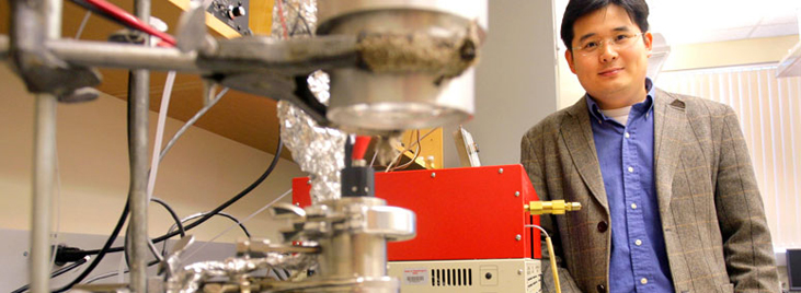 Su Ha standing by scientific equipment.