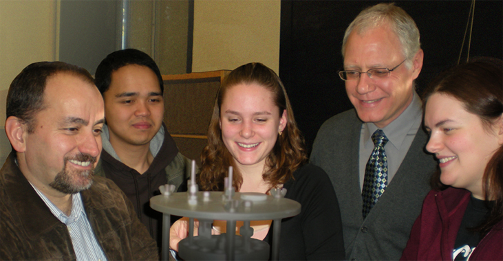 Five people looking at scientific equipment.