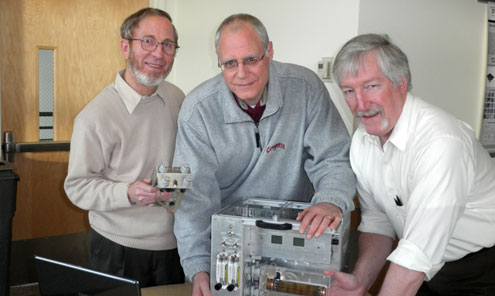 Three researchers pose with scientific equipment.