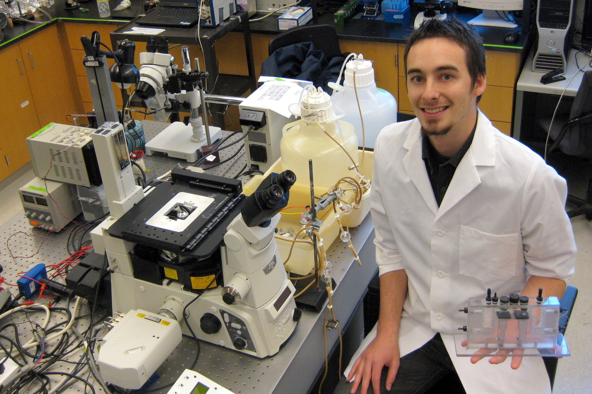 Man in lab coat surrounded by scientific equipment.