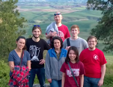 Seven people standing against a backdrop of rolling green fields.
