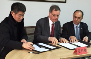 Three men singing documents at a table.