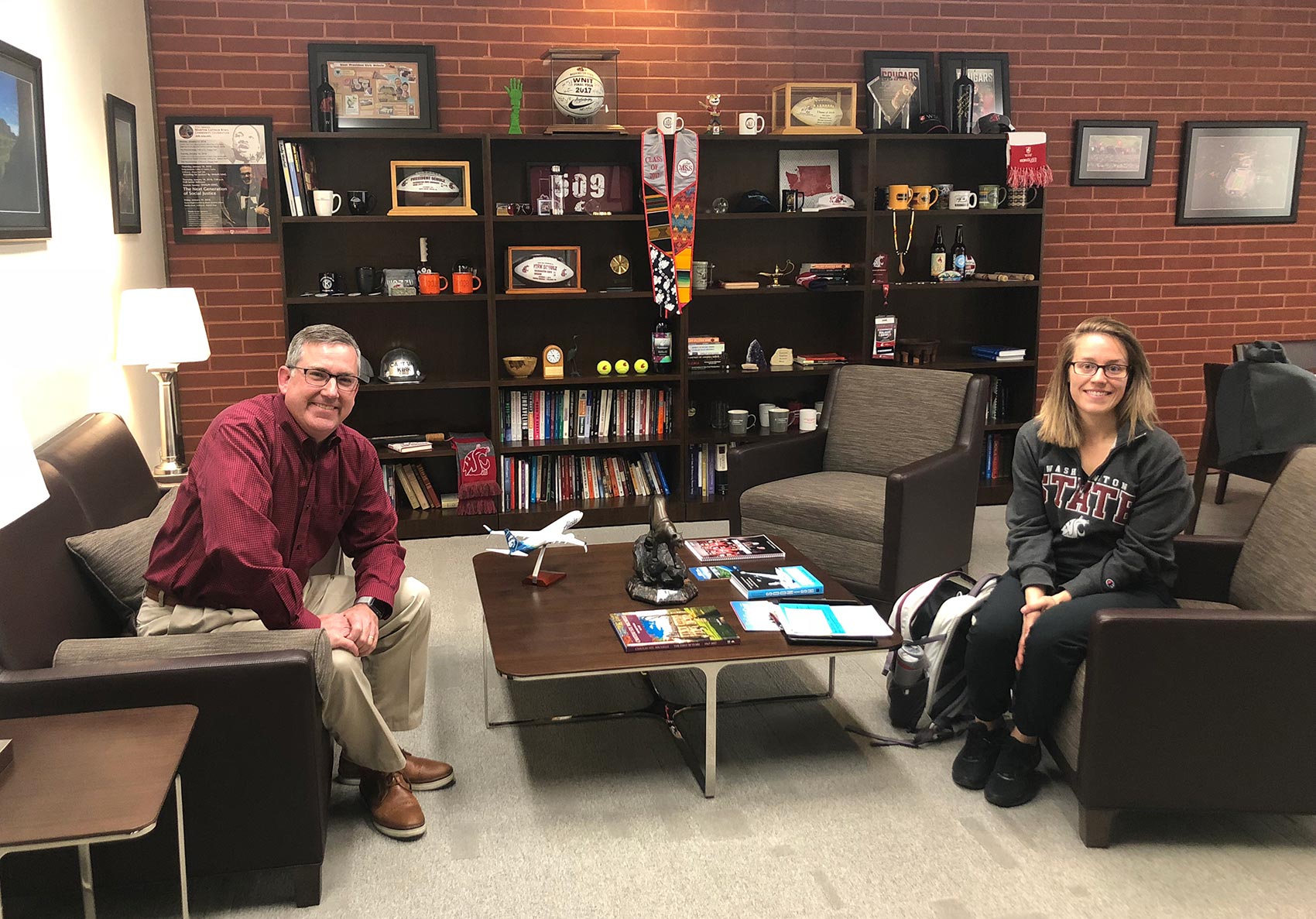Kirk sitting on a couch and Sherry sitting in an armchair in an office.