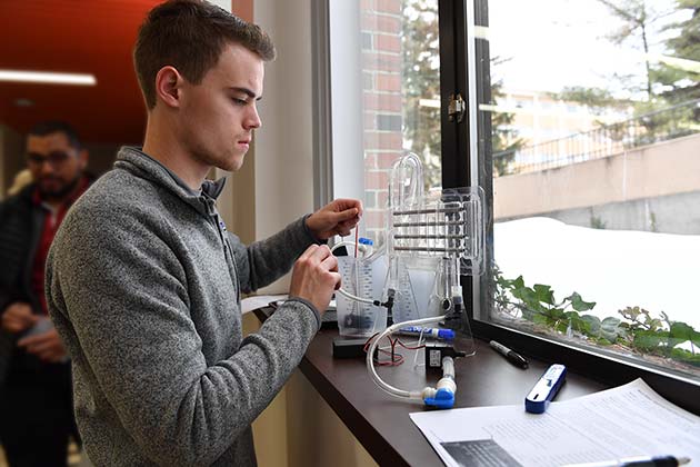 A man engaged in an experiment, standing at a desk by a window.