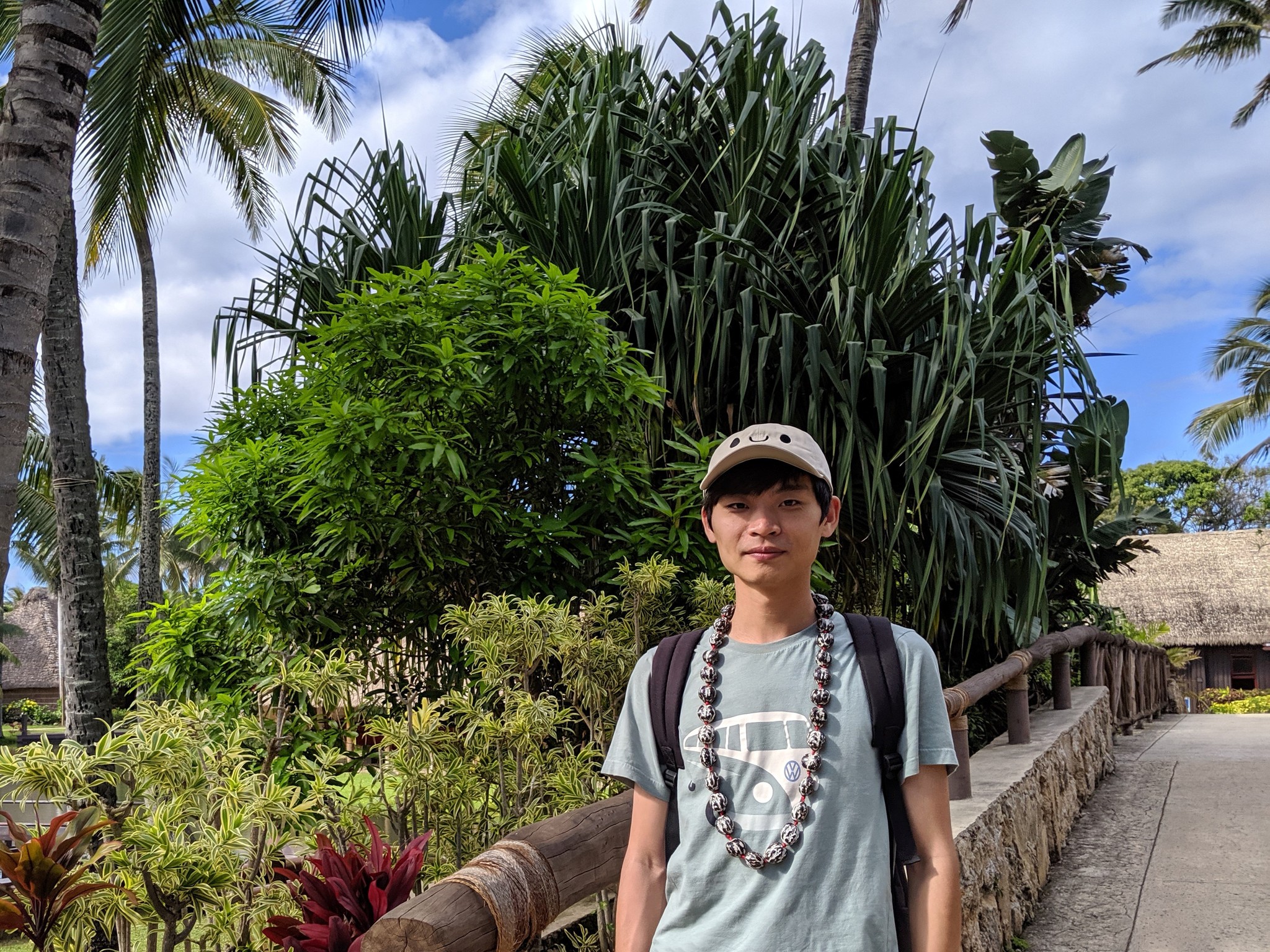 Xianglong Wang standing in front of tropical trees.
