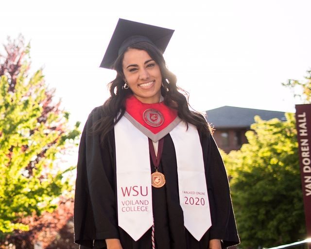 A WSU student wearing a graduation gown and red sash.