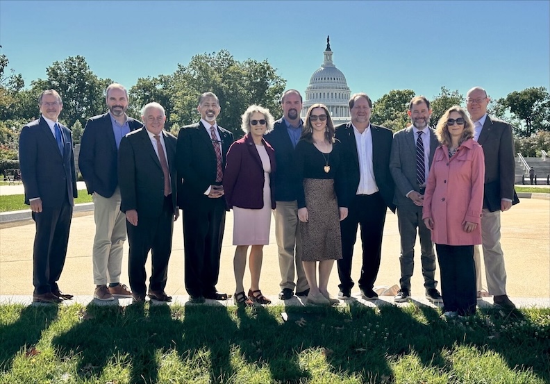 Eleven people standing on the lawn in front of the Washington DC Capitol Building.