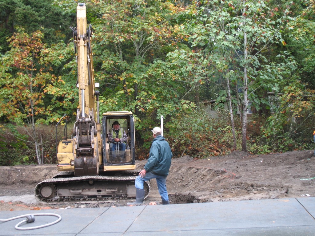Excavating the rain garden. Excavator and person standing nearby