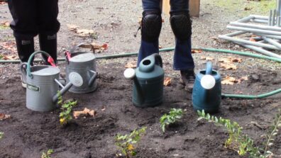 Photo of 4 watering cans with peoples feet