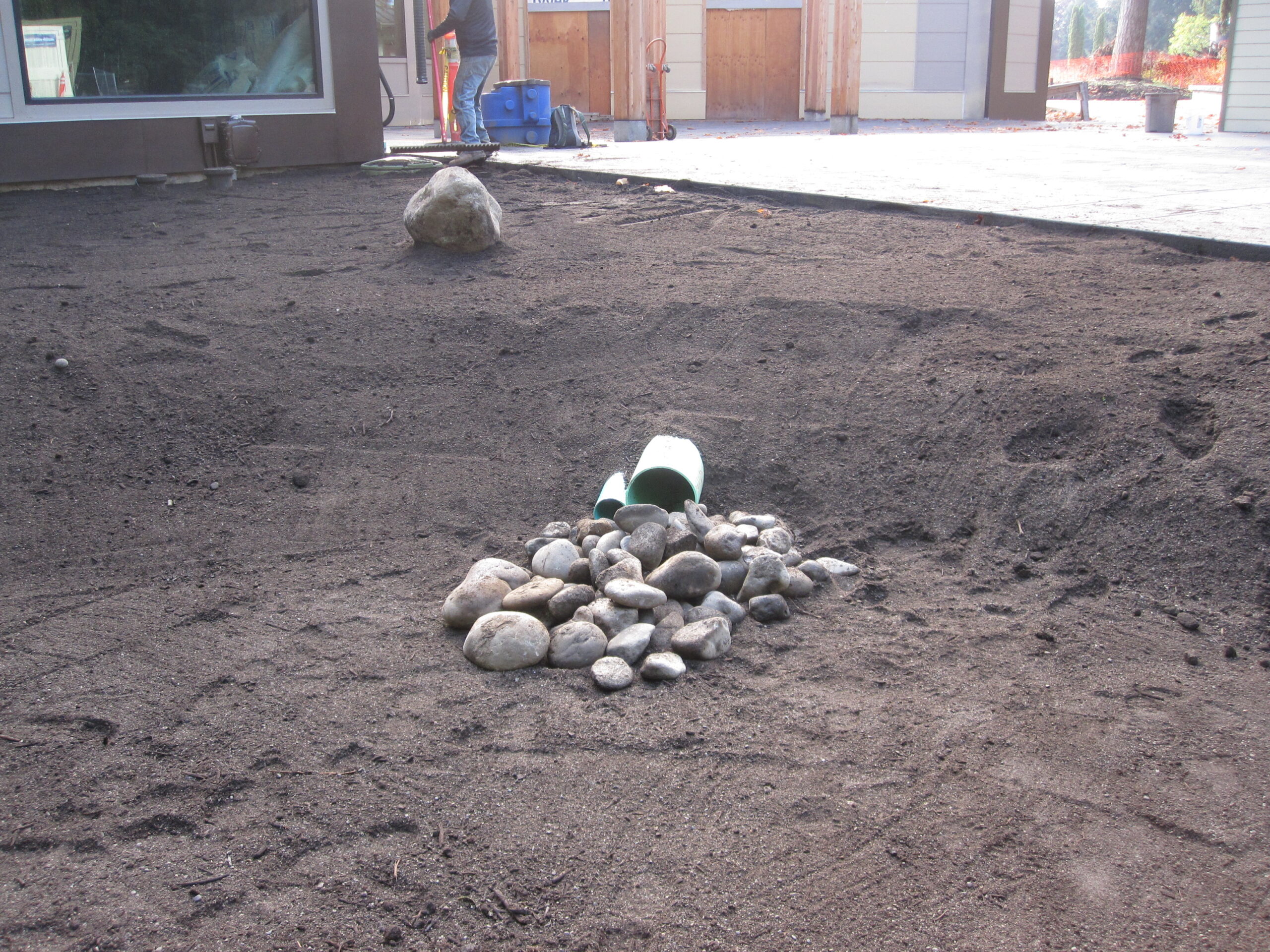 Closeup of inflow pipe with rocks taken from bottom of rain garden, before planting