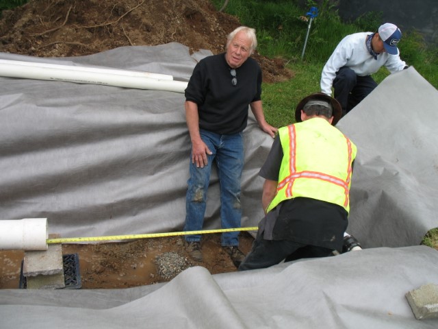 people constructing gravel infiltration trench - covering with filter fabric
