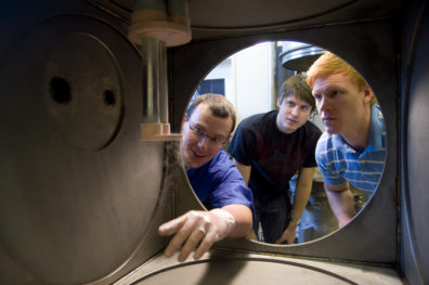 Ron Bliesner (center) examines the cryogenic chamber in Dr. Leachman's (left) lab.