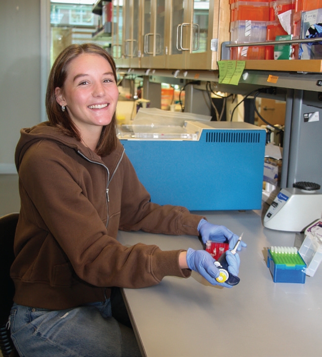 Student poses for a photo in the lab while working with a pipette