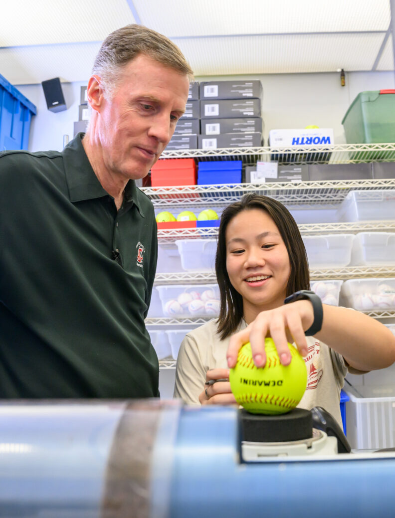 Professor Lloyd Smith and researcher measure a softball. 