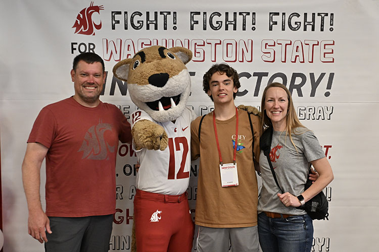 Student, their supporters, and Butch in front of the WSU Fight Song banner.