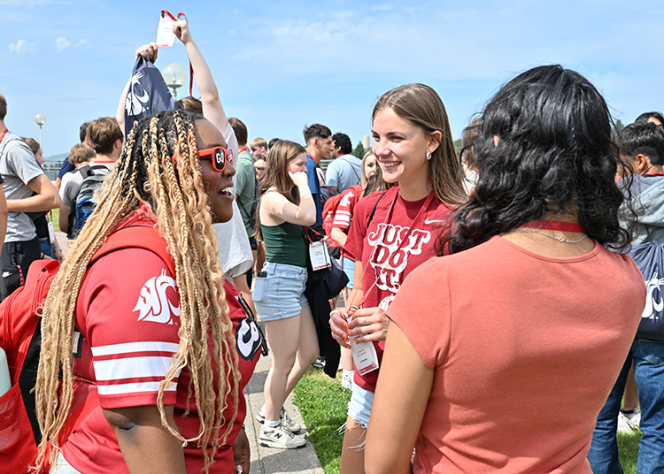 An Orientation Leader (OL) greets new Cougs at orientation.