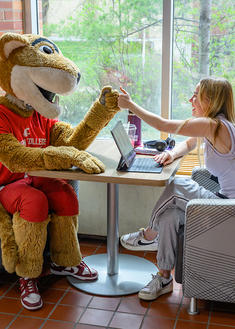 Butch high-fives a student working on a computer.