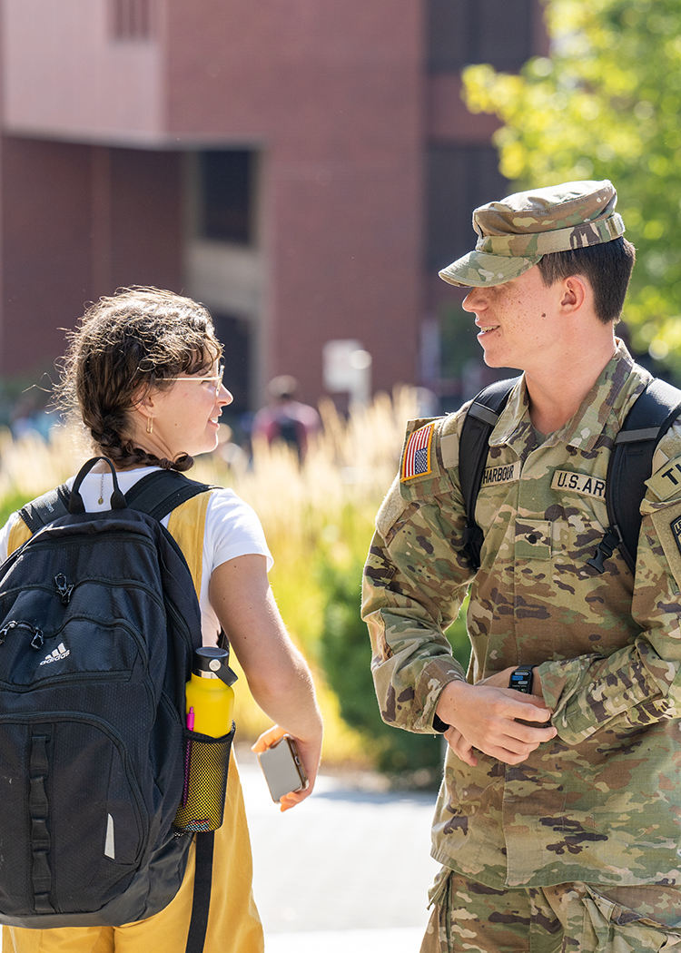 A student in military uniform stops to talk to a friend.