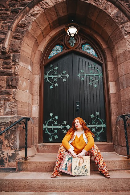 OL Cora sits in front of a giant historic door