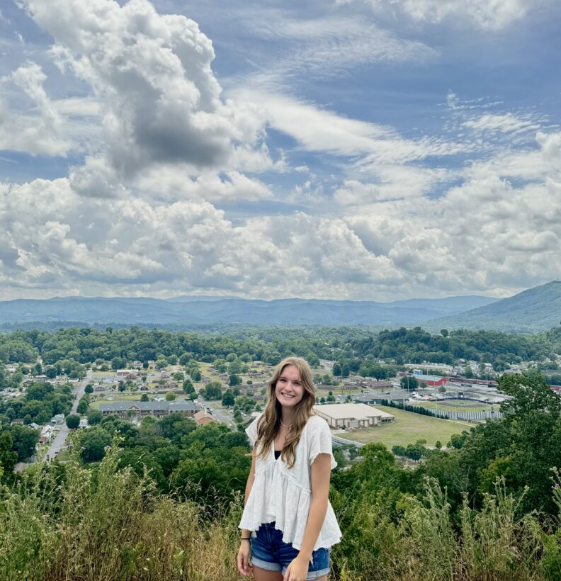 OL Lola stands on a hilltop with a beautiful sunny day in the background.