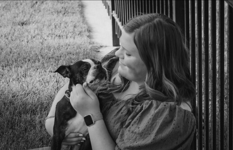 Black and white photo of OL Olivia cuddling her dog.