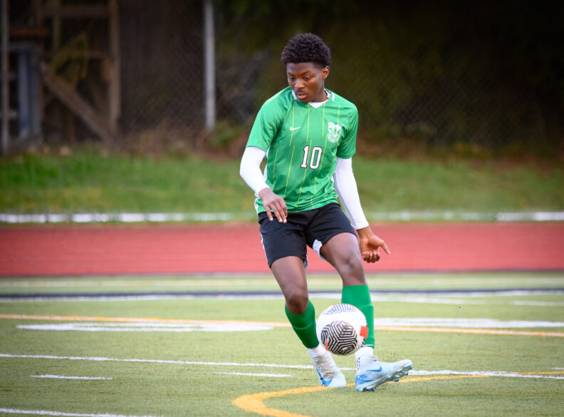 OL Sam kicks a soccer ball near midfield