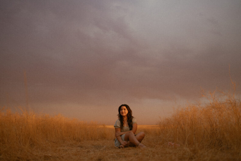 OL Yoshimi sits in the sand at golden hour.