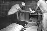 Photo of two people slicing up cheese.
