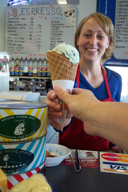 A Ferdinand's worker handing an ice cream cone to someone.
