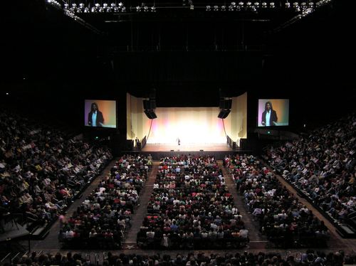 View of the stage at Beasley with a speaker projected on screens, left and right of the stage.